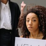 A woman holding a help sign, depicting workplace harassment in an office setting.