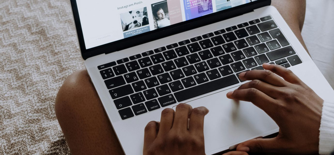 A woman browsing digital designs on a laptop while sitting comfortably at home.