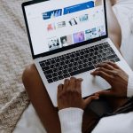 A woman browsing digital designs on a laptop while sitting comfortably at home.