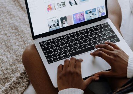 A woman browsing digital designs on a laptop while sitting comfortably at home.