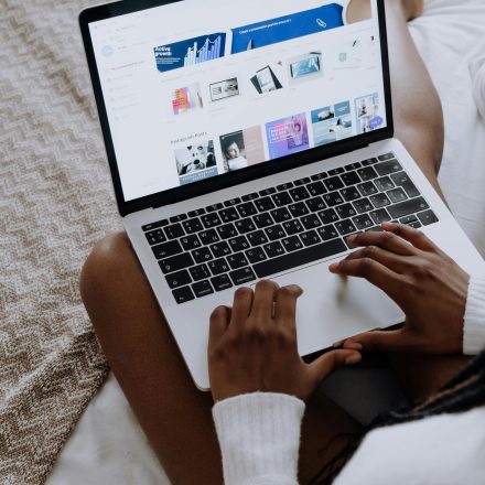 A woman browsing digital designs on a laptop while sitting comfortably at home.