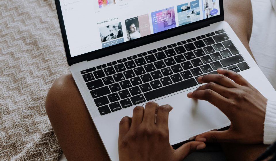 A woman browsing digital designs on a laptop while sitting comfortably at home.